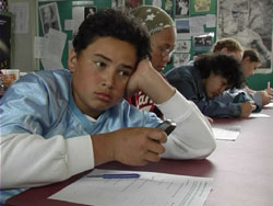 Boy texting at school desk